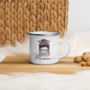 May include: White enamel mug with a black and white illustration of a woman with a pink bow in her hair and the text "INKED MAMA" in pink letters.
