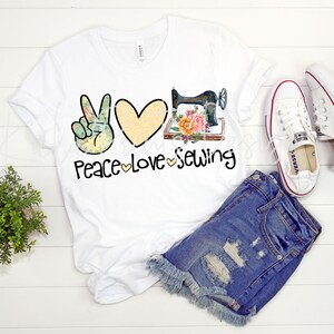 May include: White t-shirt featuring a peace sign, heart, and sewing machine graphic. The text "Peace Love Sewing" is printed below the graphic.