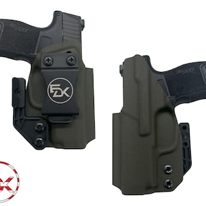 May include: Two black handguns with holsters. The holsters are green and have a black clip. The holsters have the text "FDX" on them.