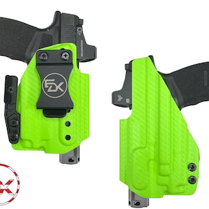 May include: Two green gun holsters with a black gun inside each. The holsters have a textured surface and a black clip. The holsters are designed to be worn on a belt.