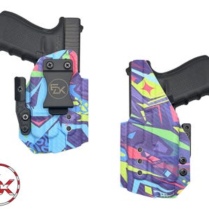 May include: A blue and purple printed holster with a black gun inside. The holster has a black clip and a black button. The holster is designed for concealed carry.