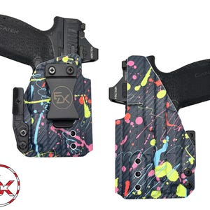 K&ouml;nnte beinhalten: Zwei schwarze Handfeuerwaffen mit Holstern. Die Holster sind mit einem schwarzen Kohlefasermuster und bunten Farbspritzern in Pink, Gelb und Blau verziert. Die Holster haben einen Metallclip und das Logo "FX" in einem Kreis.