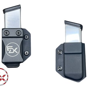 May include: Two black magazine carriers with silver magazine inserts. The carriers have a screw on each side and a logo that says "FDX" on the front.