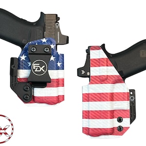May include: Two black firearms are displayed with custom holsters. The holsters feature a red, white, and blue American flag design. The holsters have a black clip and the logo "5X" is visible. The firearms have a black finish and a red dot sight.