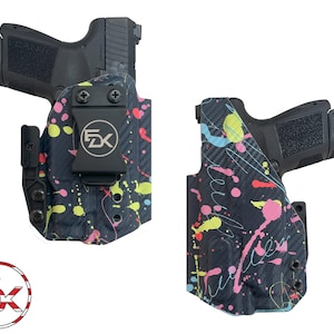 May include: Two black Kydex holsters for a handgun, each featuring a carbon fiber texture with a vibrant neon paint splatter pattern in pink, yellow, and light blue. One holster includes a black belt clip with a circular FDK logo in the center.