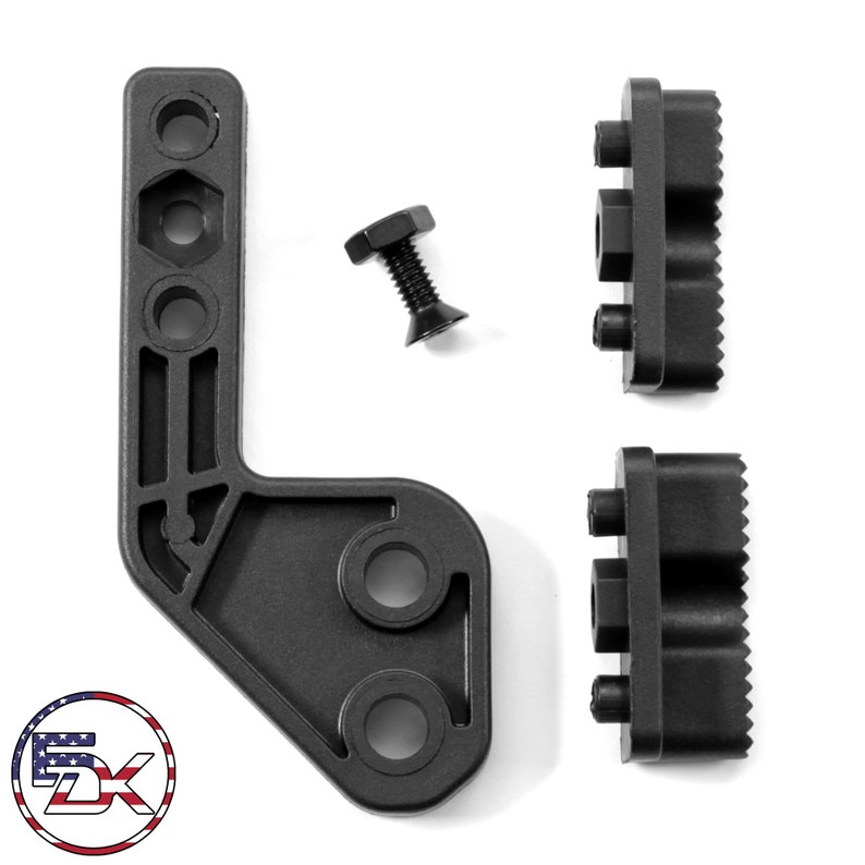 May include: A set of black metal mounting components, comprising an L-shaped bracket, two rectangular pieces with textured sides, and a bolt. The items are displayed against a white backdrop.