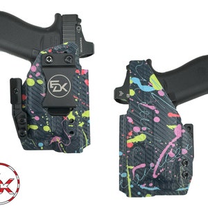 May include: A black and grey gun holster with a splatter paint design in pink, blue, green and yellow. The holster has a black clip and a black logo that says "FDX".