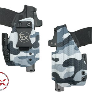 May include: A black and grey camouflage pattern holster with a black clip and a black gun inside. The holster has a black logo with the letters "FDX" in white.