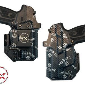 May include: Two black handguns with holsters. The holsters are black with a carbon fibre pattern and the Jack Daniel's logo. The holsters have a metal clip with the letters "FZK" on them. The handguns are black with the Ruger logo.