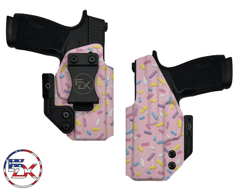 May include: A pink and white gun holster with a sprinkle pattern. The holster has a black clip and a black logo that says "FDX".