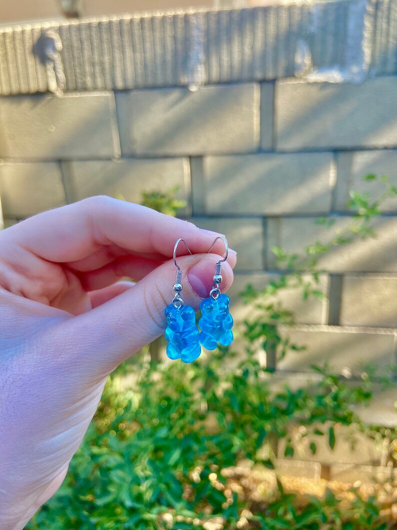 K&ouml;nnte beinhalten: Ein Paar blaue Gummib&auml;rchen-Ohrringe mit silbernen Haken.