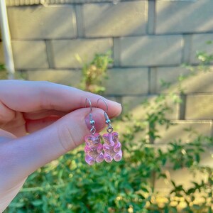 K&ouml;nnte beinhalten: Ein Paar silberne Ohrringe mit rosa Gummib&auml;rchen-Anh&auml;ngern.