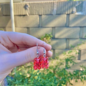 K&ouml;nnte beinhalten: Ein Paar silberne Ohrh&auml;nger mit rosa Gummib&auml;rchen-Anh&auml;ngern.