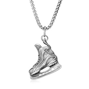 Puede incluir: Collar con colgante plateado con un charm detallado de patín de hielo. El charm, suspendido de una cadena, está diseñado para parecerse a un patín de hielo clásico, con cordones y cuchilla.