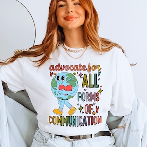 May include: White sweatshirt with a colorful graphic of a cartoon Earth holding a heart and the text "advocate for all forms of communication".