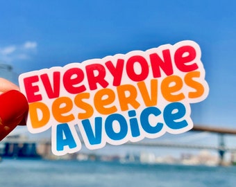 Puede incluir: Una pegatina colorida con el texto "EVERYONE DESERVES A VOICE" en rojo, naranja y azul. La pegatina se muestra sobre un fondo de cielo azul, agua y un puente.