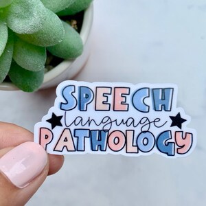 May include: A sticker with the text "SPEECH language PATHOLOGY" in colourful, stylised lettering. The sticker has a white background and black stars on either side of the text.