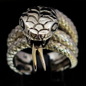 May include: A silver snake ring featuring a detailed head and forked tongue. The snake is coiled around the band of the ring.