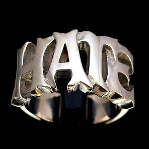Puede incluir: Un anillo de plata con la palabra "HATE" escrita en letras mayúsculas y en negrita.