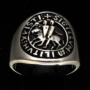 Könnte beinhalten: Ein silberner Ring mit einem schwarzen und silbernen Siegel, das einen Ritter zu Pferd zeigt. Das Siegel ist mit den Worten "SIGILLVM MILITIAE XPI" in einem Kreis angeordnet.