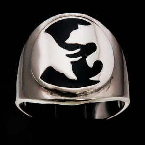 Puede incluir: Anillo de plata con un oso y un lobo abrazándose en un diseño circular. El anillo tiene un acabado pulido y una banda ancha. Los animales están sobre un fondo negro.