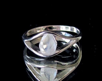 May include: A silver ring featuring a teardrop-shaped moonstone set in a delicate, open design.