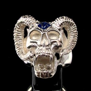 Può includere: Anello in argento a forma di teschio con corna di ariete e una pietra preziosa blu sulla fronte.