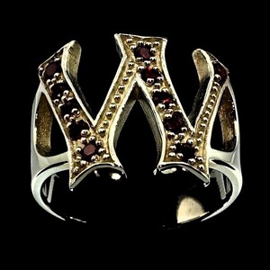 Puede incluir: Un anillo de plata con un gran diseño de letra W. La letra está bordeada de oro y adornada con piedras preciosas rojas.
