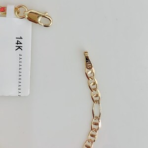 May include: A gold chain bracelet with an oval link design. The bracelet is shown with a clasp and a tag that reads "14K". The bracelet is displayed on a white background.