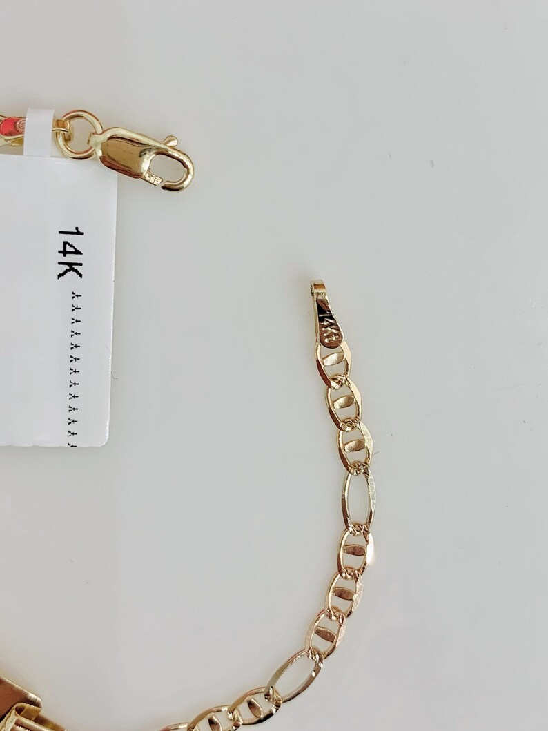 May include: A gold chain bracelet with an oval link design. The bracelet is shown with a clasp and a tag that reads "14K". The bracelet is displayed on a white background.