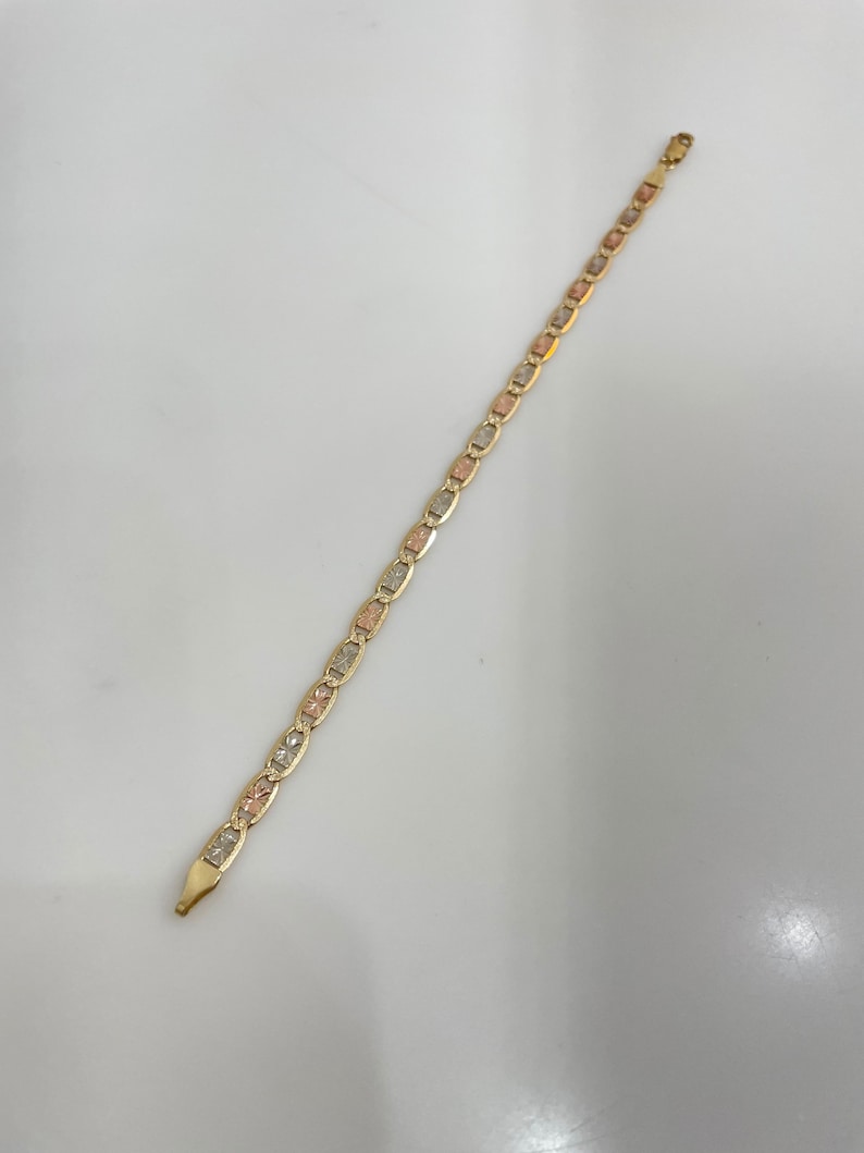 May include: A gold chain bracelet with a tri-color design. The chain is made of three different colors of gold: yellow, white, and rose.