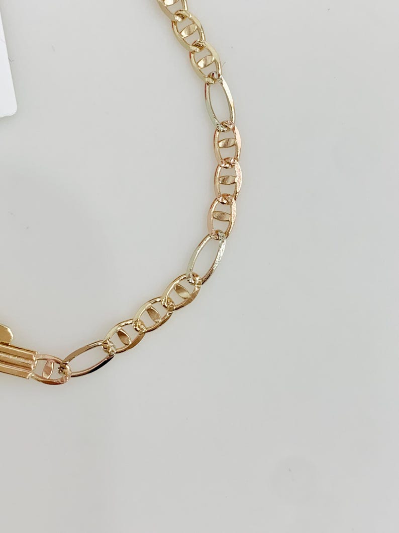 May include: A gold-coloured chain necklace featuring a combination of oval and rounded links. The chain has a bright, polished finish, reflecting light. The design is simple and elegant, suitable for everyday wear. The necklace is shown against a plain white background.