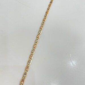 May include: A gold bracelet with a three-tone design. The bracelet is made of yellow, white, and rose gold.