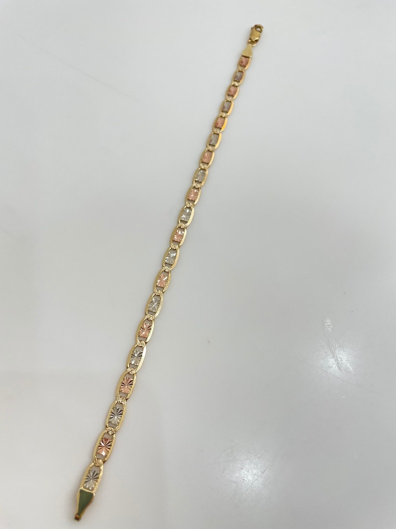May include: A gold bracelet with a three-tone design. The bracelet is made of yellow, white, and rose gold.