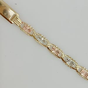 May include: Gold-toned bracelet featuring a series of textured, diamond-shaped links in yellow, rose, and white gold. The bracelet has a rectangular clasp. The design is intricate and eye-catching, suitable for everyday wear or special occasions.