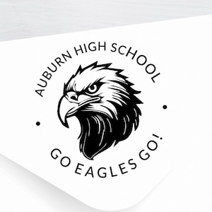 May include: A white envelope with a black and white circular sticker. The sticker features an eagle head with the text "Auburn High School Go Eagles Go!"