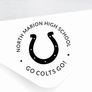 May include: A white envelope with a black and white round sticker. The sticker has a horseshoe, the words "North Marion High School", and "Go Colts Go!"