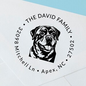 May include: A black and white illustration of a Rottweiler dog with a happy expression. The illustration is part of a round return address stamp that reads "The David Family, 32098 Mitchell Ln, Apex, NC 27502."