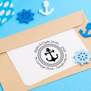 May include: A white envelope with a return address label featuring a nautical themed design. The label has a black anchor inside a rope circle with the text "Jayda & Clyde Smith 711 Carriage Drive - Temple Hills, HI- 32421".