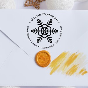 May include: A white envelope with a black and white snowflake return address stamp. The stamp reads "Jillian Randolph, 394 Shady Lane, Lagrange, GA 30240". A gold wax seal is on the envelope.