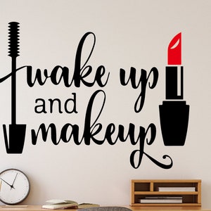 May include: Black and white wall decal with the text "Wake up and makeup" and a black mascara wand and red lipstick.