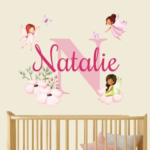 Puede incluir: Adhesivo de pared con el nombre "Natalie" en rosa, una gran "N" rosa, hadas, flores y mariposas. Ideal para una habitación infantil, el diseño tiene un tema de cuento de hadas.