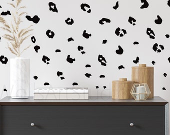 May include: A black and white leopard print wall decal with a black dresser and decorative wooden boxes on top.