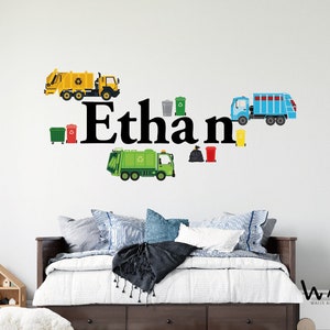 May include: A wall decal featuring the name "Ethan" in black letters with a yellow, green, and blue garbage truck design. The decal includes various colored recycling bins and garbage bags.