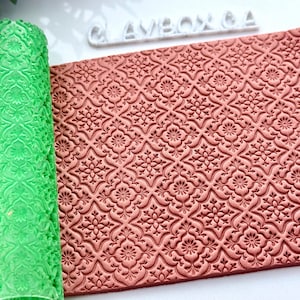 May include: A rolled green patterned sheet and a terracotta-colored sheet with a floral design. The sheets are likely for crafts or baking, with the word "CLAYBOX GA" in white letters in the background.