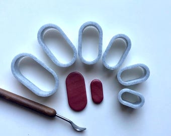 May include: A set of seven oval-shaped cookie cutters in various sizes, made of white speckled plastic. Two small oval-shaped pieces of red clay are also included.