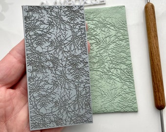 May include: Two gray textured polymer clay stamps with a branch pattern. The stamp on the left is a raised design and the stamp on the right is a recessed design.