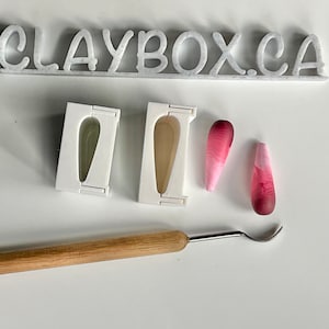 May include: Two white silicone moulds for making teardrop-shaped polymer clay earrings. Two finished earrings are shown, one pink and white and the other red and white. A wooden tool is also shown.