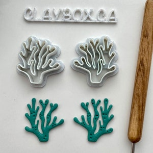 May include: Set of four coral cookie cutters, two white and two teal green. The cutters are shaped like coral branches. The image also includes a rolling pin and a small tool.