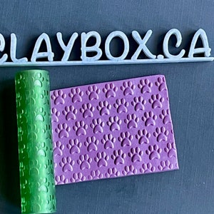Peut inclure: Rouleau à pâtisserie vert avec un motif de patte de chien et un tapis en silicone violet avec un motif de patte de chien. Le rouleau à pâtisserie et le tapis sont utilisés pour faire du fondant ou de la pâte polymère.